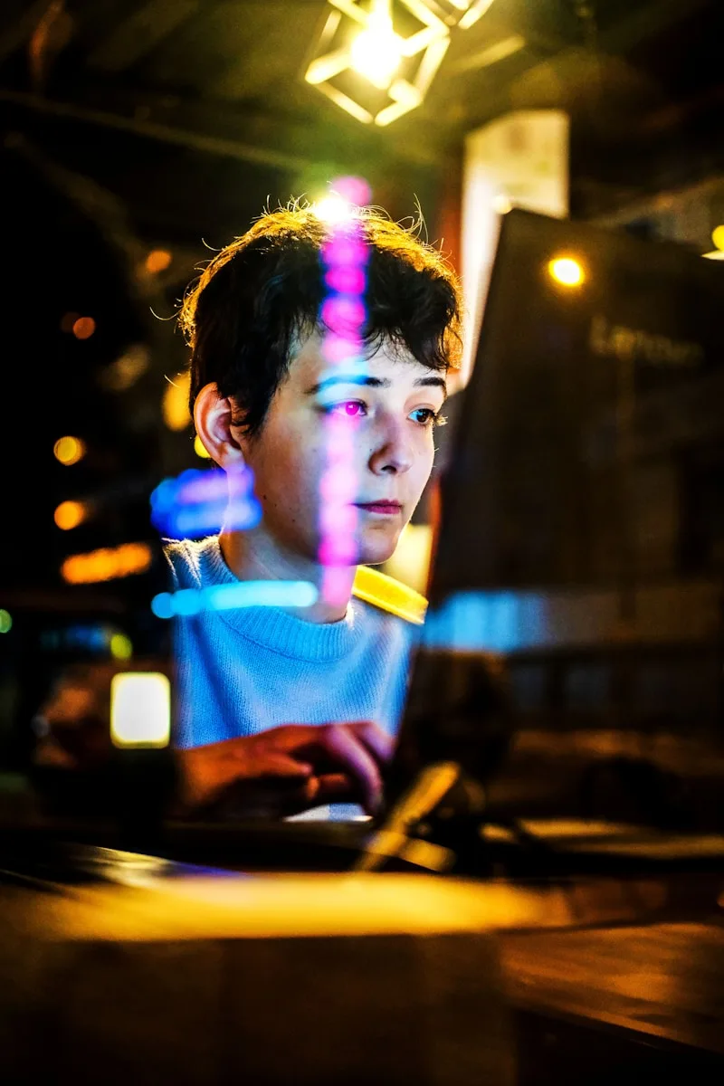 a young boy sitting in front of a laptop computer
